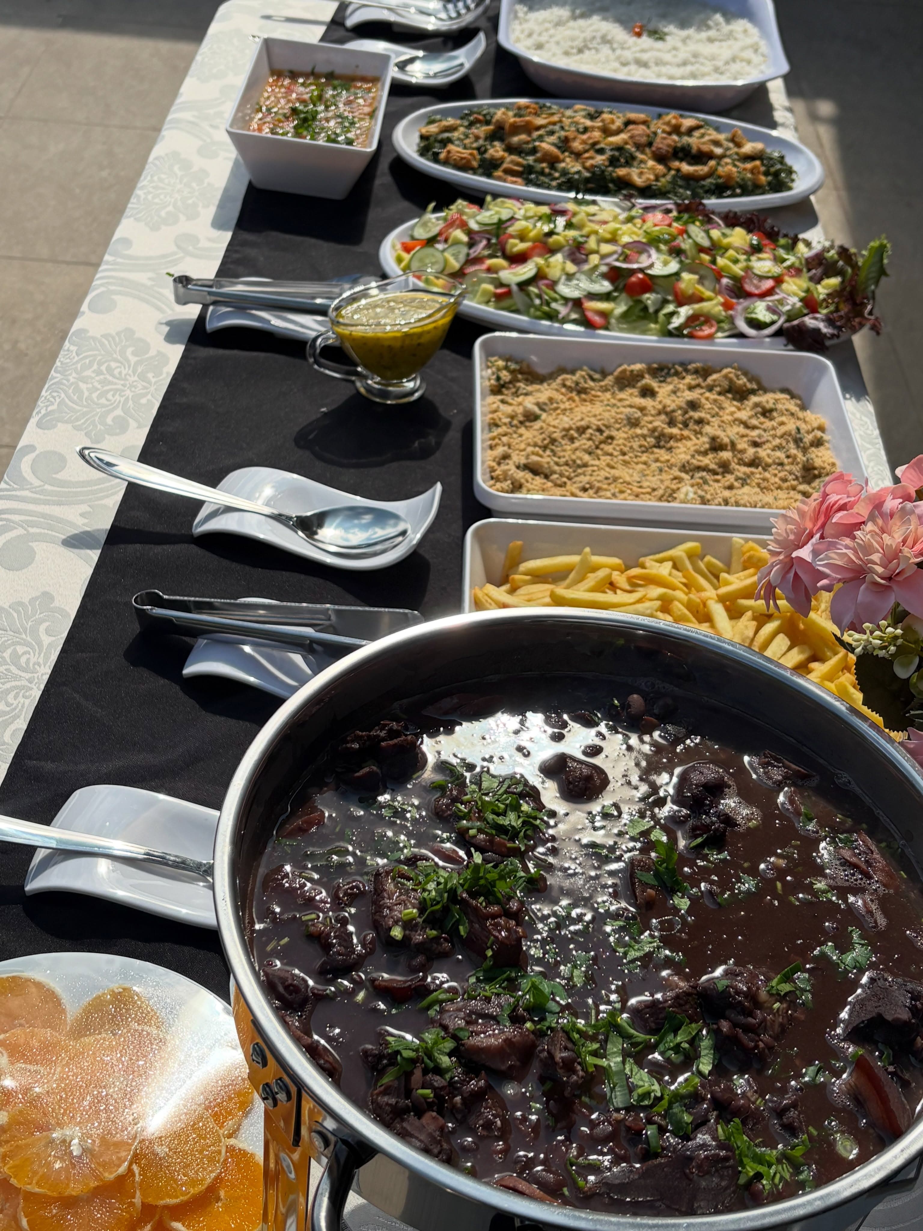 Buffet de feijoada com arroz, salada, farofa, batata e acompanhamentos.